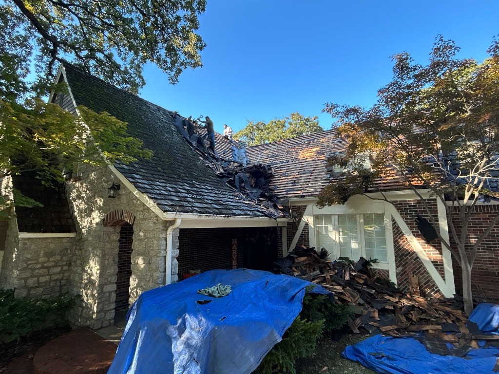 Workers performing a tear-off on a steep-pitched residential roof